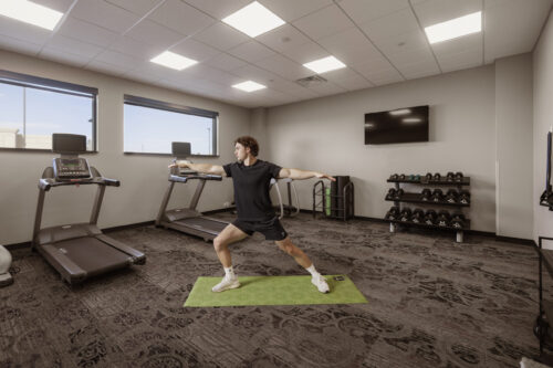 A man practicing yoga on a green mat in the fitness center at The Parker Hotel.