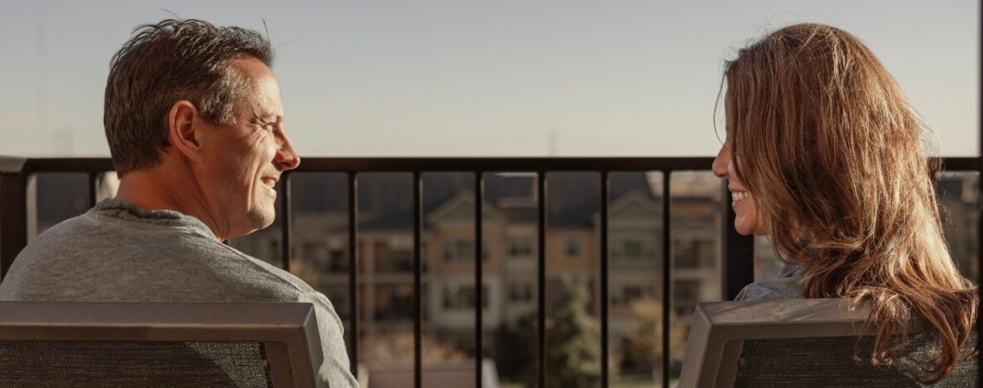 A couple sitting on a balcony at sunset.