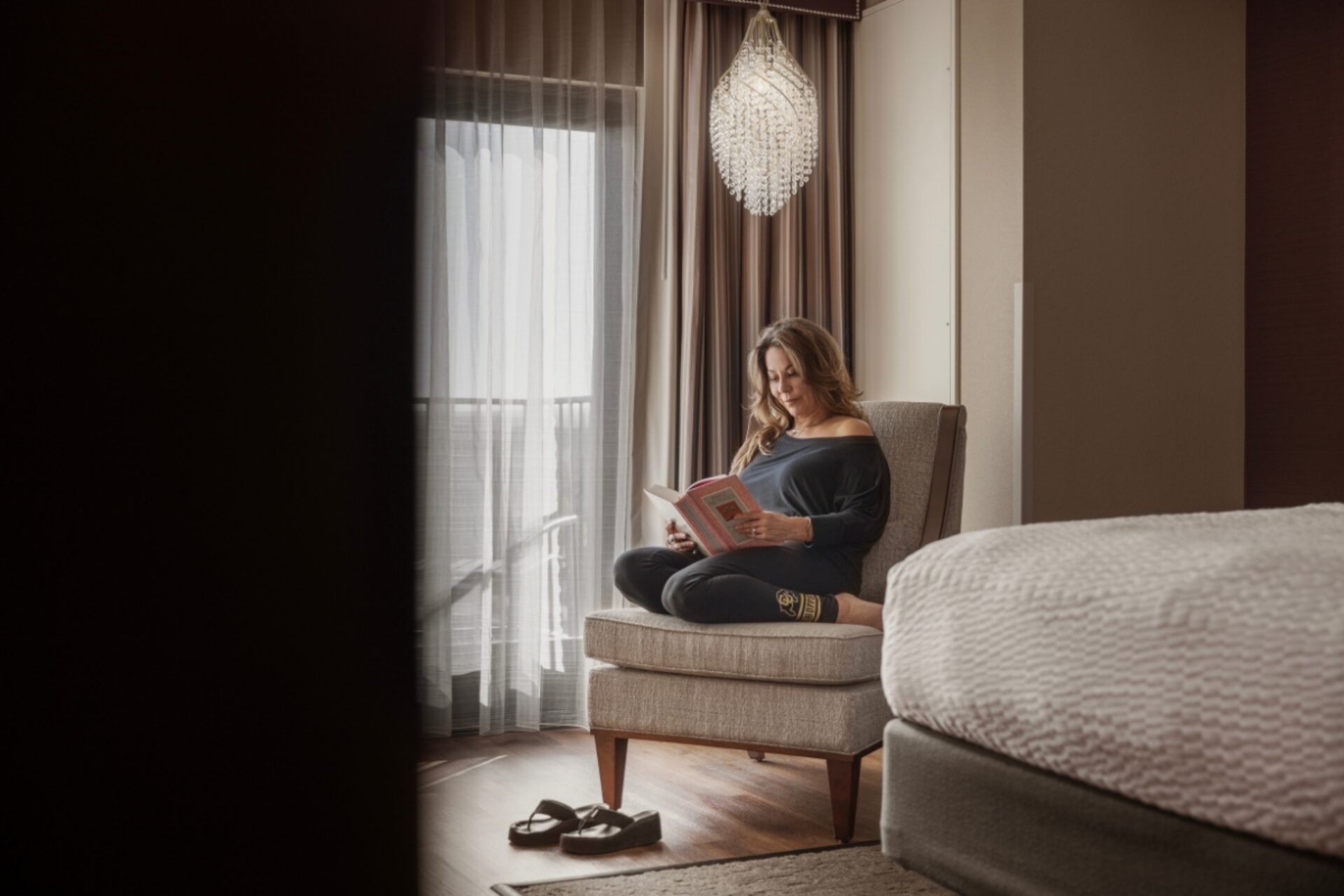 A woman reading in a chair by the window.
